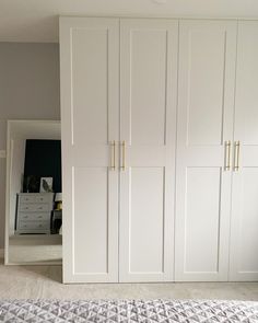 a bedroom with white closets and carpeted flooring in front of the bed