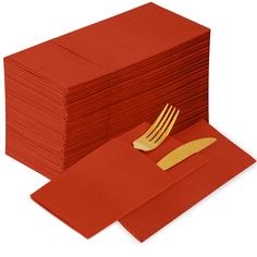 a stack of red napkins with gold forks on top of each folded in orange paper