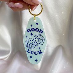 a hand holding a keychain that says good luck with dices on it