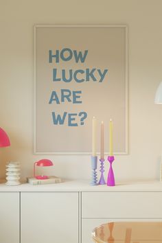 a poster that says how lucky are we? on the wall above a table with candles