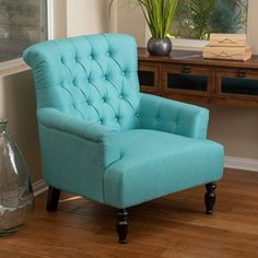 a blue chair sitting on top of a hard wood floor next to a vase filled with flowers