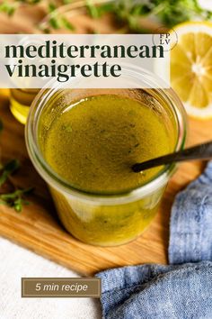 a jar filled with green liquid next to sliced lemons on a wooden cutting board