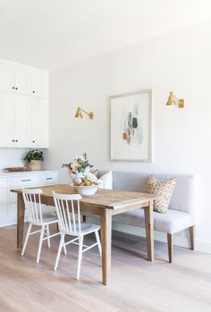 a kitchen and dining room with white cabinets, wood flooring and wooden table in the center