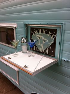 two martinis are sitting on a table in front of an old camper trailer