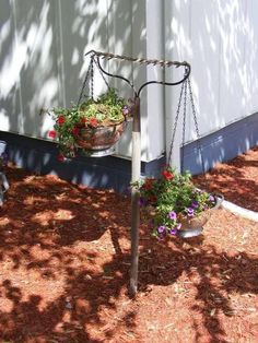 two potted plants hanging from a metal pole with chains attached to the top and bottom