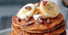 a stack of pancakes topped with bananas and nuts