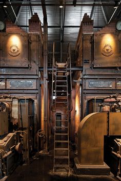 there are many machines in the factory with stairs leading up to them and some boxes on the floor