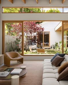 a living room with couches and chairs in front of large windows