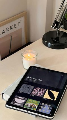 an ipad sitting on top of a table next to a candle