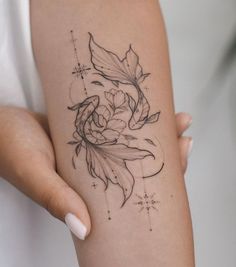 a woman's arm with a fish and flower tattoo on the left side of her arm