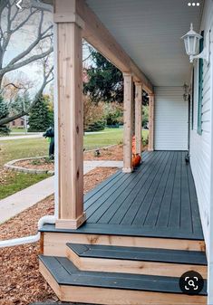 a porch with steps leading up to the front door and an orange pumpkin sitting on top of it