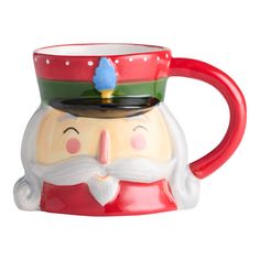 a ceramic mug with a santa clause on it's face and a red handle