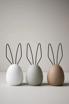 three eggs with bunny ears on them sitting next to each other in front of a white wall