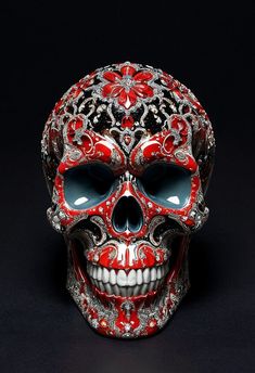 a red and silver skull with ornate designs on it's face, against a black background