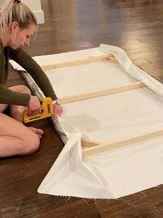 a woman sitting on the floor working with construction materials