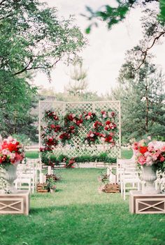 an outdoor ceremony set up with white chairs and red flowers