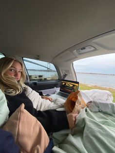 a woman sitting in the back seat of a car with a laptop on her lap