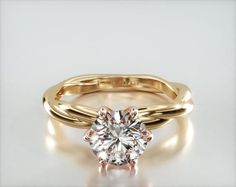 a yellow gold engagement ring with a round cut diamond in the center and side stones on each band