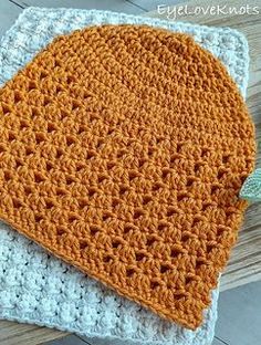 an orange crocheted hat sitting on top of a wooden table