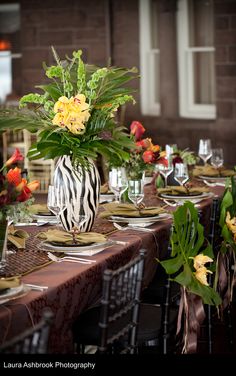 a table set with plates and vases filled with flowers