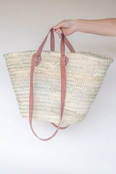 a hand is holding a large woven bag