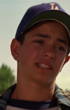 a young boy wearing a baseball cap and looking at the camera