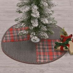 a small christmas tree sitting on top of a table next to a present box and ribbon