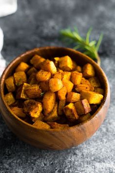 a wooden bowl filled with cubed potatoes on top of a gray counter next to a napkin