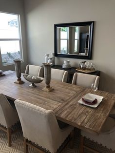 a dining room table with white chairs and a large mirror on the wall above it