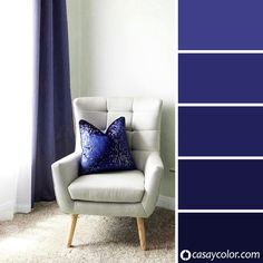 a white chair sitting in front of a window next to a blue and white wall