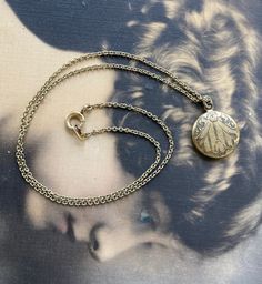 "Here is a brass metal etched charm and a chain necklace. The chain is small and this was probably for a child.  The pendant is not a locket. The charm measures 1/2\" across.  The charm is hollow metal with forgetmeknot flowers on the front and plain on the back. The chain measures 12 3/4\" long and has a early spring clasp on the end. Metal is not pristine.  There are some scratches on the back of the pendant. The chain and the pendant are not marked. Brass has aged. There are no marks on the c Brass Medallion Charm Necklace With Vintage Charm, Brass Round Pendant Charm Necklace With Vintage Charm, Vintage Brass Medallion Charm Necklace, Engraved Brass Medallion Charm Necklaces, Engraved Medallion Brass Charm Necklaces, Engraved Brass Medallion Charm Necklace, Engraved Medallion Charm Necklace In Brass, Vintage Charm Brass Medallion Necklace, Vintage Brass Engraved Charm Necklace