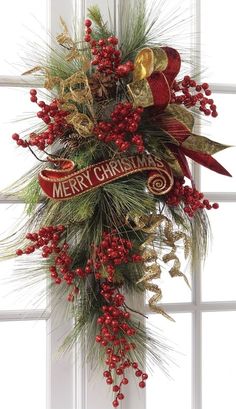 a christmas wreath hanging on the front door with red berries and pine cones around it