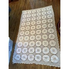 a white crocheted blanket sitting on top of a wooden floor