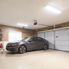 a car is parked in a garage with two overhead lights on the ceiling above it