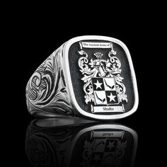 a black and white photo of a ring with two coats of arms on the front