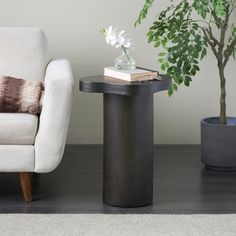 a white chair sitting next to a table with a book on it and a potted plant