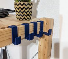 a wooden shelf with blue brackets attached to it and a potted plant on top