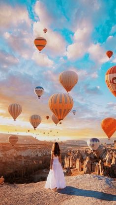 a woman standing on top of a hill next to hot air balloons