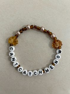 a beaded bracelet with the words catch me on it, and an orange leaf