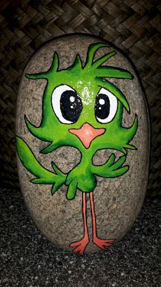 a green bird painted on top of a rock