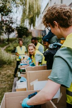 a group of people in yellow vests and blue gloves unpacking boxes outside