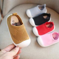 someone is holding their baby's slippers in front of three different colors and sizes