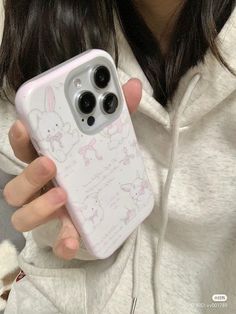 a woman holding up her phone case in front of her face