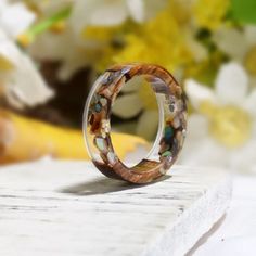 a close up of a wooden ring on a table with flowers in the back ground