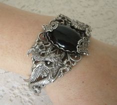 This beautiful silver plated filigree cuff bracelet has silver plated dragons, silver plated accents and a black onyx setting. Adjustable. Medieval Style Silver Jewelry With Intricate Design, Gothic Silver Bracelet, Silver Gothic Bangle, Silver Dragon Design Jewelry For Formal Occasions, Medieval Style Bangle Jewelry Gift, Silver Fantasy Jewelry For Formal Occasions, Silver Jewelry With Dragon Design For Formal Occasions, Formal Silver Jewelry With Dragon Design, Gothic Metal Jewelry With Dragon Design