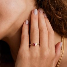 a close up of a person wearing a gold ring with a pink stone on it