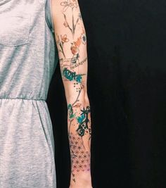 a woman's arm with tattoos on her left arm and the other arm is covered in flowers