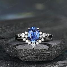 a blue and white diamond ring sitting on top of a black stone slab with diamonds around it