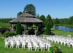 an outdoor wedding venue with white chairs and a gazebo