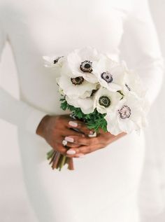 a woman holding a bouquet of white flowers